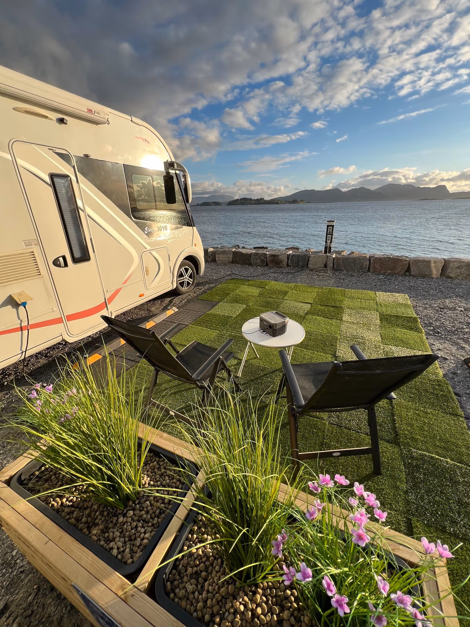 Sitteplass på kunstgress ved en bobil og havet